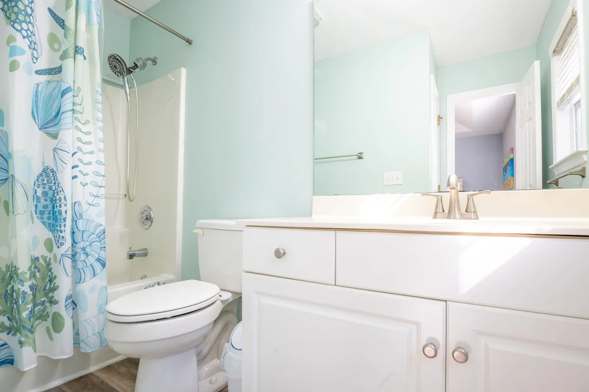 A sparkling clean bathroom with a bathtub, sink, and shower curtain. The space is tidy and inviting, embodying family-friendly convenience.