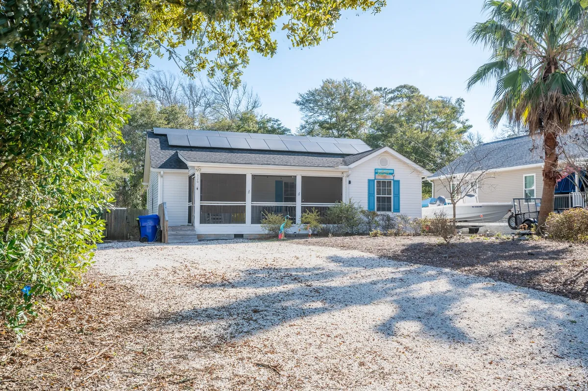 A classic front porch with solar panels overlooks a lush, landscaped garden. The inviting porch and open yard hint at both relaxing mornings and the possibility of letting your pup enjoy the grassy expanse. The scene feels welcoming and laid-back, echoing the island's easygoing lifestyle.